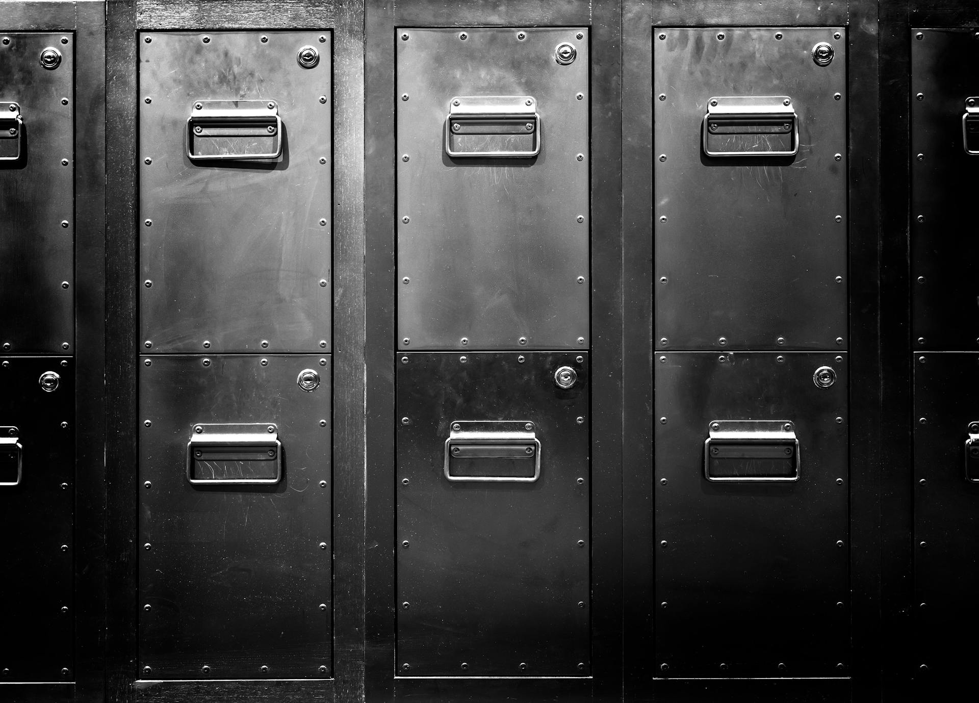 A black and white image showing a wall of old secure filing cabinets